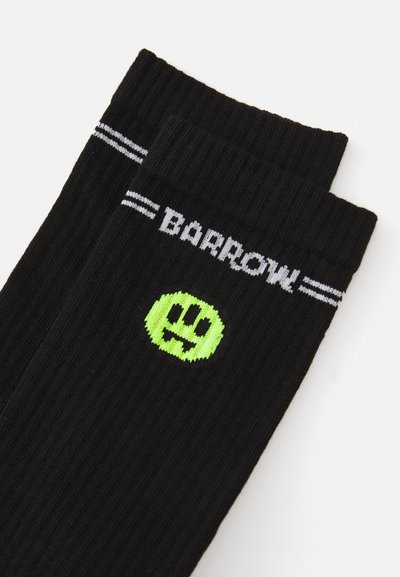 Calze nere a coste con un logo di faccina sorridente verde e il testo bianco "BARROW" con due strisce orizzontali nella parte superiore.