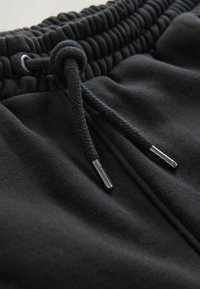 Sorte joggerbukser med en tekstureret elastisk talje, justerbar snor med metaltips og blødt stof.