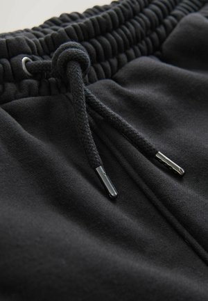 Schwarze Jogginghosen mit elastischem, strukturiertem Bund, verstellbarem Kordelzug mit Metallspitzen und weichem Stoffgefühl.