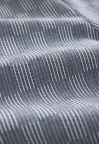 Tissu bleu-gris avec des fines lignes blanches verticales régulièrement espacées, montrant des plis doux et la texture.