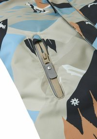 Wasserabweisende Jacke in einem beige-blauen Farbschema, mit strukturiertem Stoff, der abstrakte Muster aufweist, und einem seitlichen Reißverschluss.