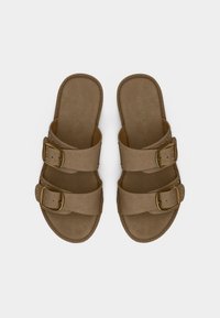 Paire de sandales en daim marron avec deux brides à boucles dorées et petites clous dorés, vues de dessus sur fond blanc.