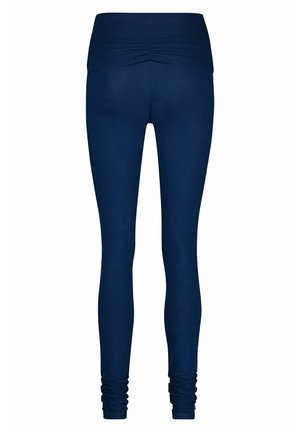Marineblaue Leggings mit einer engen Passform, breitem, gerafftem Bund und gerüschten Knöcheldetails, hergestellt aus einem dehnbaren, glatten Material.