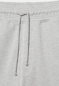 Taille de pantalon de jogging gris clair avec bande élastique et cordons noués suspendus devant au centre.