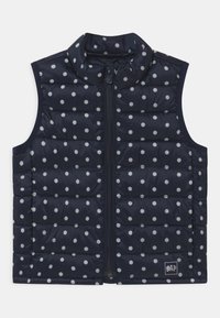 Námořnická prošívaná vesta s bílými puntíky, se zipem vpředu, vysokým límcem, polstrovaným designem a logem na dolním pravém rohu.