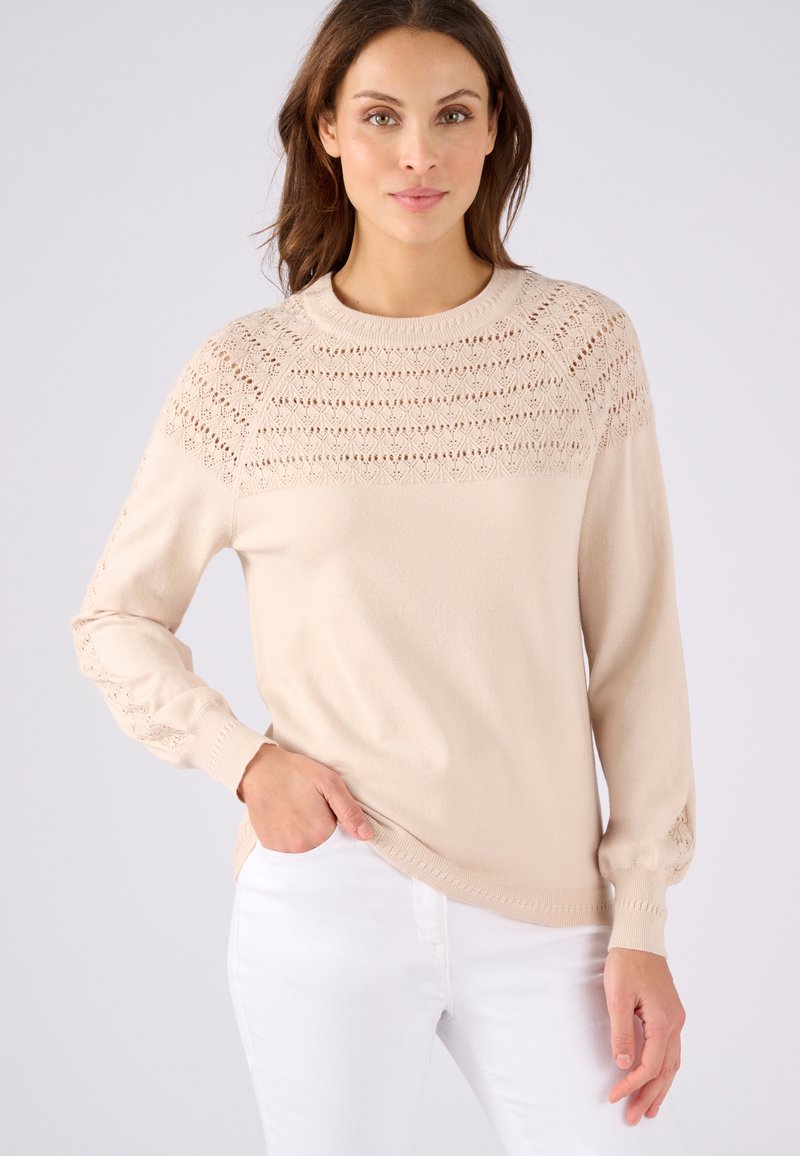 Beige trui met een ronde hals, geribbelde manchetten en verfijnde kantbrei details op de schouders en mouwen. Zachte textuur, casual pasvorm.