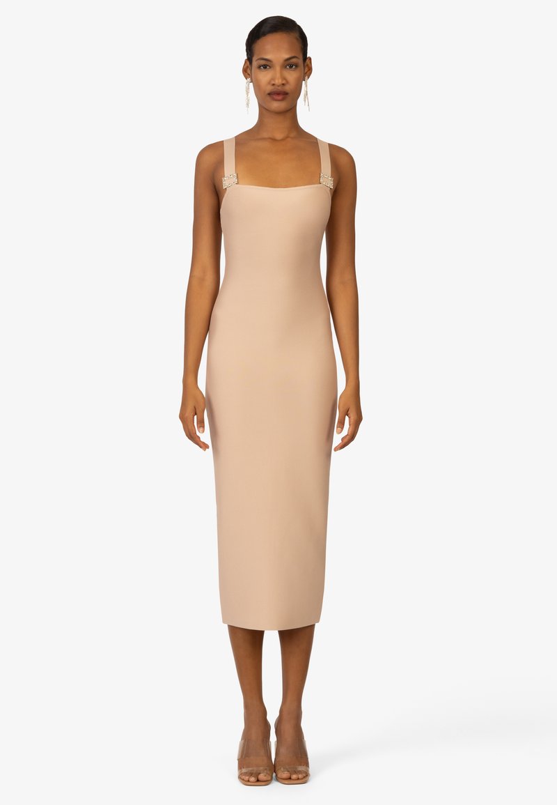 Abito midi aderente color nude con scollatura quadrata e spalline larghe che presentano dettagli in metallo argentato. Tessuto liscio, design minimalista.
