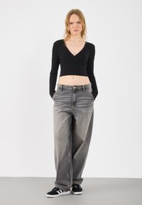 Un top scurt negru, cu dungi, cu mâneci lungi, asociat cu blugi largi, de culoare gri, cu talie înaltă și ușor decolorati. Tenisi negri cu talpă și detalii albe.