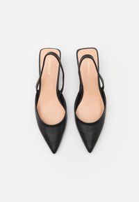 Mustad varvastega slingback-adid mustast nahast, avatud külgedega ja beežide sisetaldadega. Minimaalne disain ja peen siluett.
