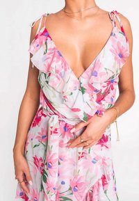 Květinové šaty s volánkovým výstřihem do V, vyrobené z lehké látky se vzorem růžových, červených a zelených květin. Obsahují detail vázání v pase.