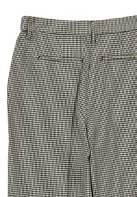 Gros plan sur un pantalon à motifs pied-de-poule brun et blanc, avec deux poches arrières passepoilées et des passants de ceinture à la taille.