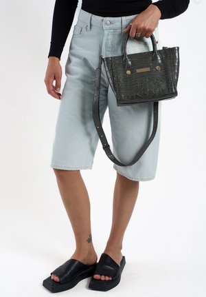 Lichtblauwe denim bermuda-shorts, zwarte leren instapsandalen en een gestructureerde donkergrijze handtas met schouderriem en gouden accenten.