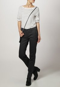 Camisa de rayas blanca y negra con escote amplio; pantalones negros ajustados; botas de tobillo; bolso de hombro con correa delgada; texturas suaves.