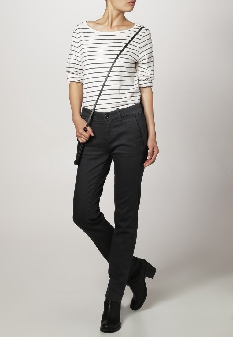 Camisa de rayas blanca y negra con escote amplio; pantalones negros ajustados; botas de tobillo; bolso de hombro con correa delgada; texturas suaves.