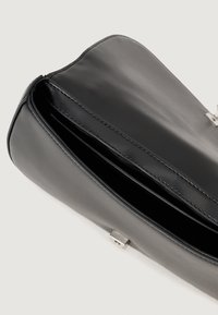 Juodas odinis rankinukas su lygiu paviršiumi, užtrauktuku ir sidabriniais akcentais. Viduje yra du skyriai. Minimalistinis dizainas.