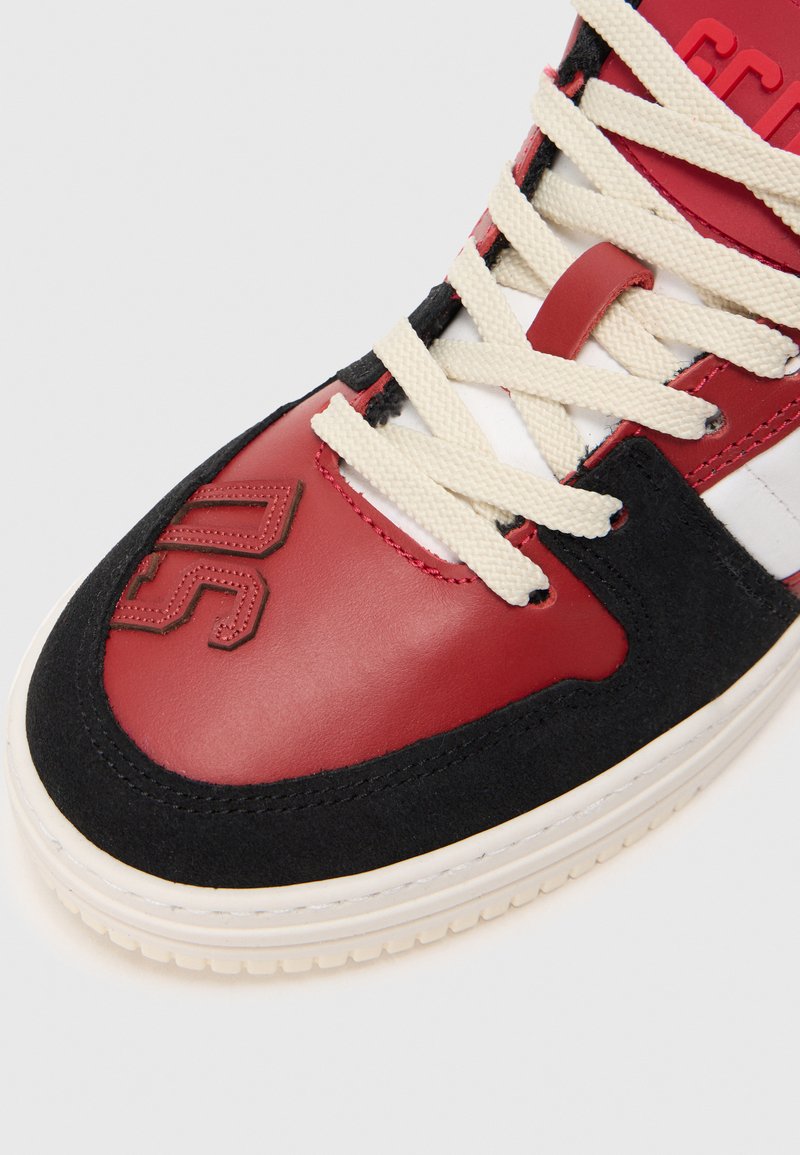 Baskets montantes rouges et noires en cuir et daim, avec des lacets crème, un détail de logo sur le bout et une semelle intermédiaire blanche.