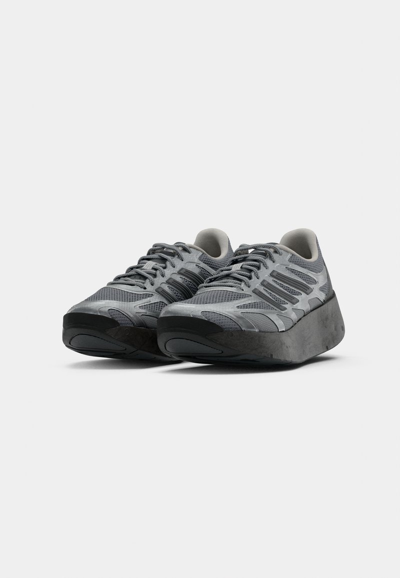 Ein Paar moderne graue Sportschuhe mit dicken, erhobenen schwarzen Sohlen und Obermaterial aus Mesh, nebeneinander auf einem weißen Hintergrund platziert.