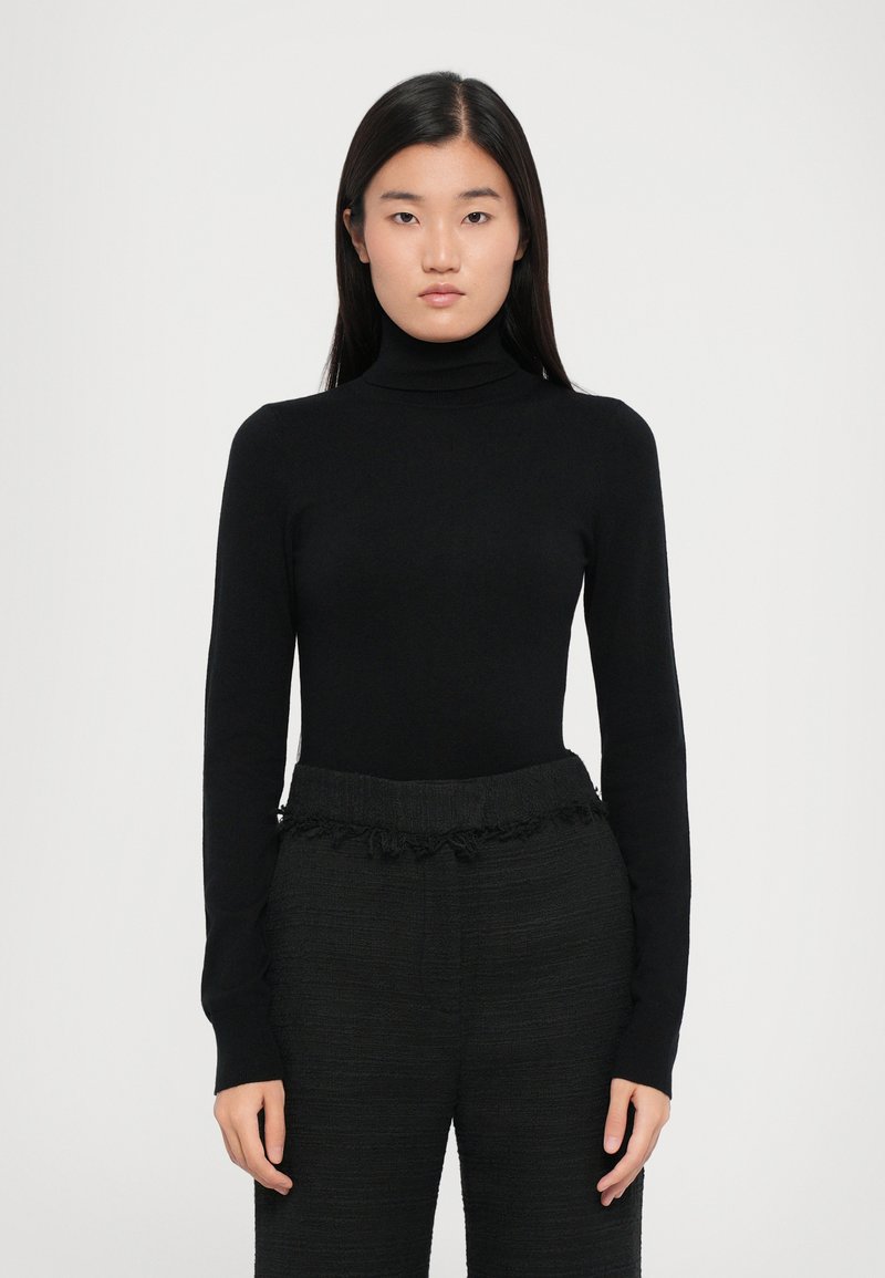 Must muströöviga must turtleneck-sviiter, taljejoon on istuv, valmistatud siledast materjalist. Kombineeritud mustade tekstuuriga pükstega, millel on kortsus vöökoht.