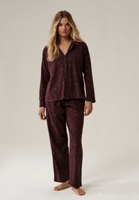 Burgundowy zestaw piżamy z miękkiego materiału, składający się z długiego, button-up topu z długim rękawem i dopasowanych spodni, zdobiony małymi wzorami w kształcie półksiężyca.
