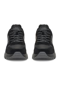 Melnas sporta kurpes ar zamšādas un acs materiālu kombināciju. Tām ir pelēkas šņorītes, polsterēta mēle un teksturēta gumijas zole.