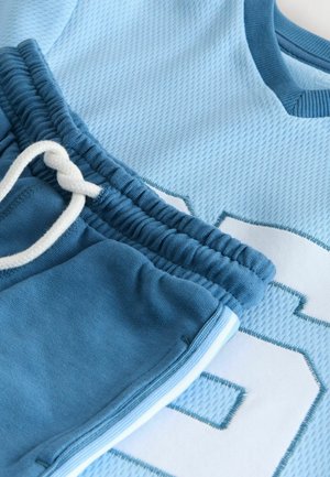 Light blue athletic top with textured mesh and large white number. Coordinating blue sweatpants with elastic waistband and drawstring.