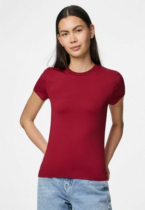 Camiseta roja ajustada de manga corta y cuello redondo, hecha de una tela suave. Combinada con jeans de color azul claro, presenta un diseño casual.