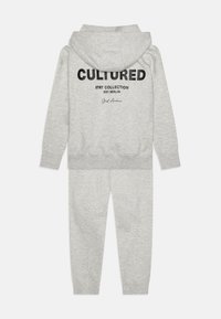 Súprava šedej mikiny a teplákov. Mikina na zadnej strane má čierny grafický nápis "CULTURED". Mäkko materiál, voľný strih, elastické manžety a pás.