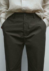 Donkerbruine broeken met een gladde textuur, voorzien van een platte voorkant, zijzakken en een enkele knoopsluiting op de taille.