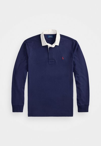 Mornarska polo majica s dolgimi rokavi v temno modri barvi z belim ovratnikom, izvezena sponka na prsih in gumbasta zapenjanja; narejena iz bombažnega blaga.