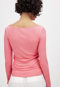 Gara piedurkne, ribota augšdaļa gaiši rozā ar plašu kakla izgriezumu. Mīksta tekstūra, pieguloša dizaina, šuvju detaļas gar muguru.