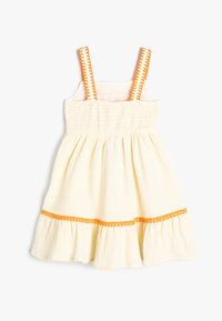 Lys gul kjole med smocket bodice, udvidet nederdel, orange kant og elastiske stropper med zigzagmønster. Tekstureret stof.