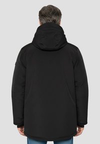 Sort hættejakke med glat ydre, elastiske manchetter og lige snit. Bagsiden har et rent design uden synlige logoer.