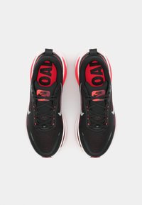 Baskets de course noires et rouges avec une tige en mesh, un col rembourré et un branding bien visible. La semelle présente des détails accentués en blanc et rouge.
