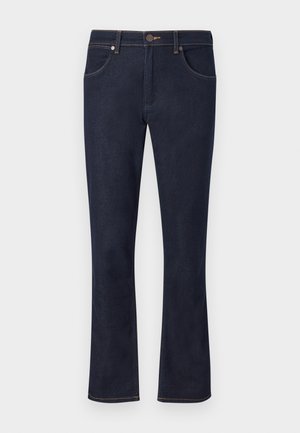 Jeans évasés bleu marine en denim avec deux poches avant et une fermeture à bouton. Présente des détails de surpiqûres contrastantes le long des coutures.