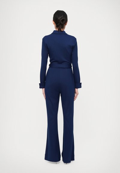 Navy blauwe jumpsuit van gladde stof, met een kraaghalslijn, lange mouwen en flared pijpen met knoopmanchetten.