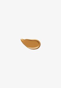 Fond de teint liquide dans une teinte marron chaud, présentant une texture lisse et brillante avec une forme de goutte légèrement courbée et allongée.
