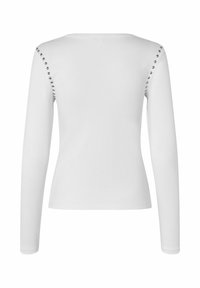 Top bianco a maniche lunghe con un design aderente. Presenta una texture a coste e borchie decorative argento lungo le cuciture delle spalle.