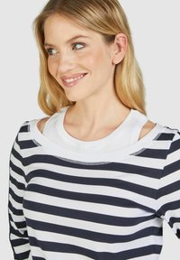 Gestreiftes Langarmoberteil in Marineblau und Weiß, mit ausgeschnittenem Schulterdesign und Rundhalsausschnitt mit kontrastierendem Besatz.