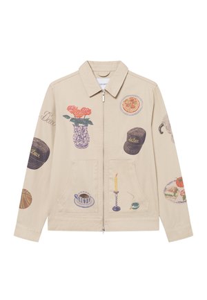 Beige canvas jacket featuring various artistic prints including flowers, food, and household items. Zipper front and two front pockets.