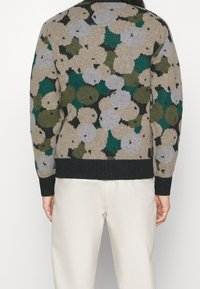 Gestrickter Pullover mit einem floralen Muster in erdigen Tönen von Beige, Grün und Grau; verfügt über einen schwarzen gerippten Saum und Ärmelabschlüsse.