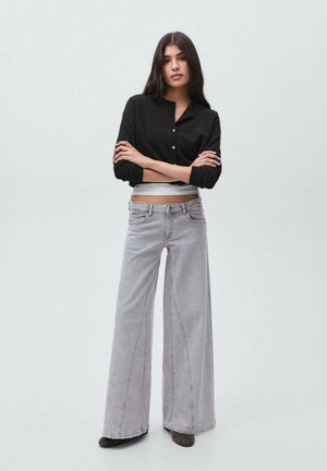 Black textured cropped button-up shirt paired with light grey wide-leg jeans featuring contrasting stitching and a slight flare at the hem.