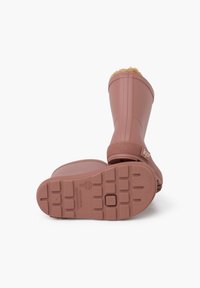 Roze rubberen regenlaarzen hebben een gestructureerde zool, een nepbontvoering aan de bovenkant en een logo aan de zijkant. Het ontwerp is van middellange laars hoogte.