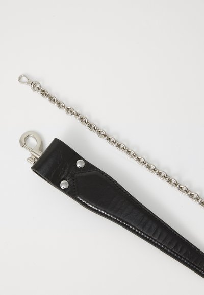 Fekete bőrszíj ezüst hardware-rel, amelyen egy rögzítőcsipesz és díszes szegecsek találhatók, kiegészítve egy ezüst lánc linkes kiegészítővel.