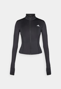 Giacca nera aderente con zip, realizzata in tessuto elastico, con maniche lunghe, colletto alto e un piccolo logo sul lato sinistro del petto.