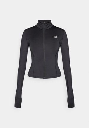 Chaqueta negra ajustada con cremallera hecha de tejido elástico, con mangas largas, cuello alto y un pequeño logo en el lado izquierdo del pecho.