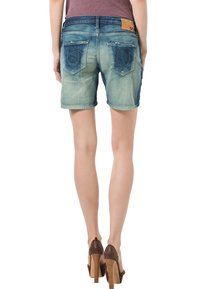 Bermudas de mezclilla con un degradado azul desvanecido, dos bolsillos traseros con costura decorativa y una etiqueta de cuero en la cintura.