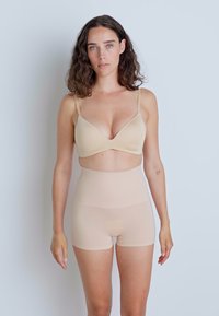 Reggiseno senza cuciture in tonalità nuda con spalline regolabili e un delicato dettaglio centrale, abbinato a pantaloni a vita alta modellanti in tonalità nuda. Texture liscia.