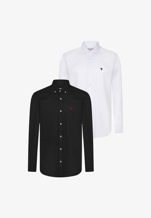 Deux chemises à manches longues : l'une noire avec un logo d'oiseau rouge, l'autre blanche avec un logo d'oiseau bleu. Les deux ont des cols boutonnés et des boutons contrastants.