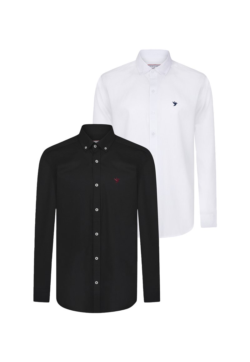 Dos camisas de manga larga: una negra con un logo de pájaro rojo, la otra blanca con un logo de pájaro azul. Ambas tienen cuellos abotonados y botones de contraste.