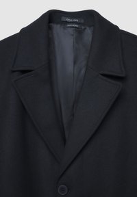 Cappotto in misto lana nera con ampi revers, chiusura a singolo bottone e fodera interna satinata, etichettato "Calliope."